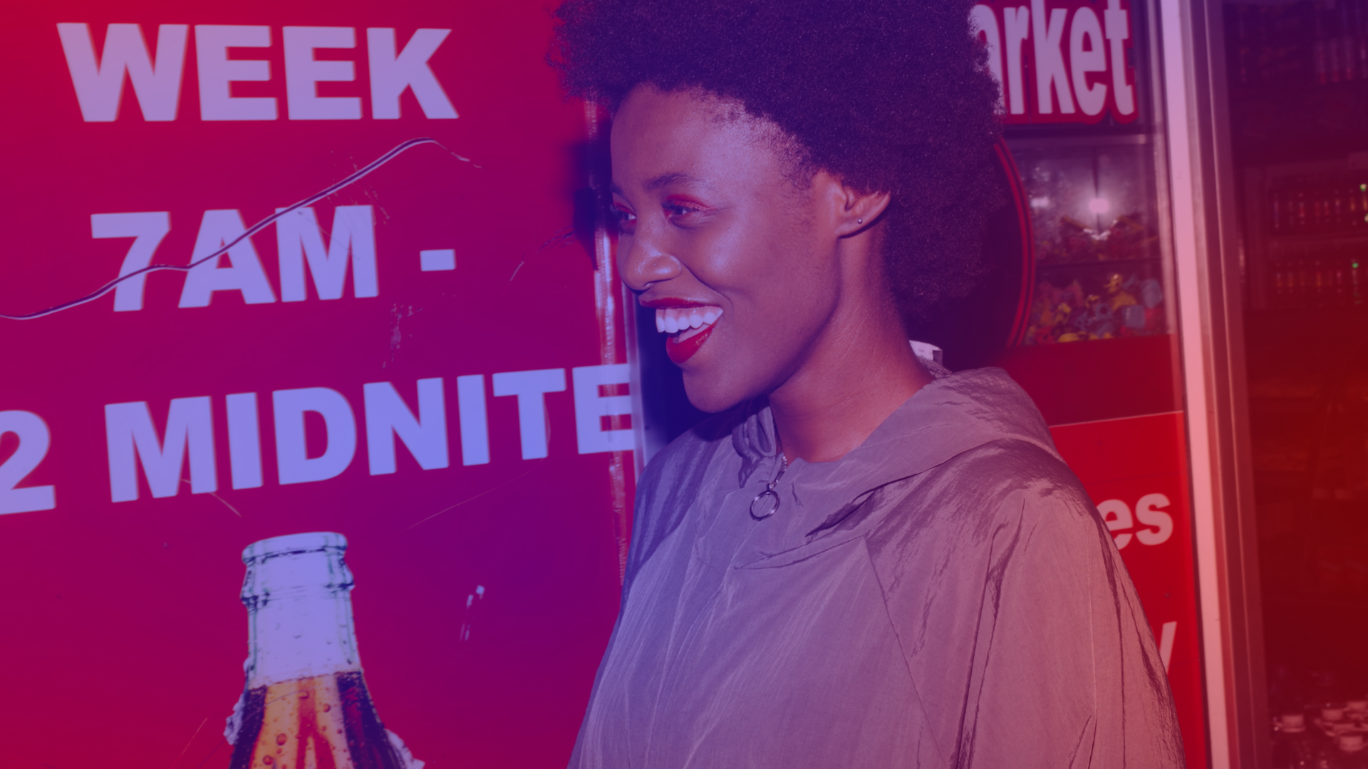Woman wearing red lipstick laughs in front of a store lit up in red – image symbolizing emotional advertising with everyday relevance.